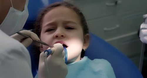 Dentist in the Dental Office Woman Dentist Treating Teeth to Little Girl Child Patient in Clinic