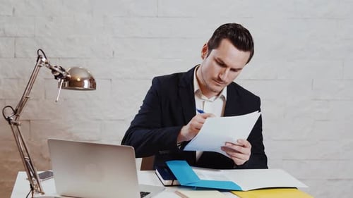 Focused Man Reviews Documents in Bright Office