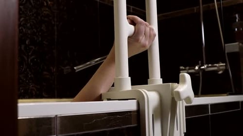 Hand Gripping Bathtub Safety Bar in Dark Bathroom