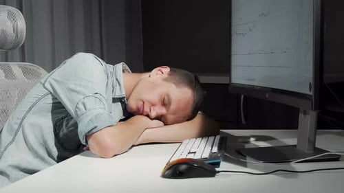 Young Adult Sleeping at Computer Desk at Night
