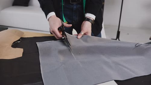 Tailor Cutting Gray Fabric with Scissors in Studio