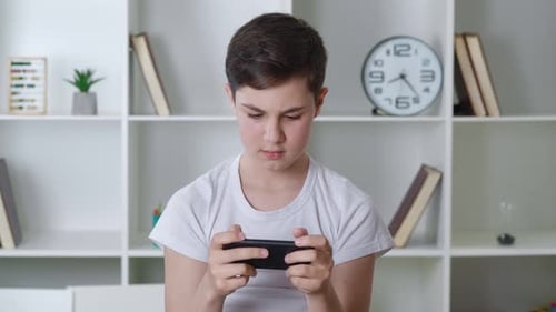 Teen boy engrossed in playing on smartphone