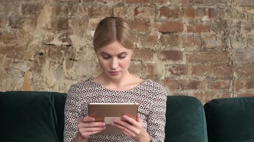 Woman Using Tablet on Couch Indoors