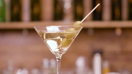 Clean Close Up Parallax Shot of a Martini Glass Garnished with Olives