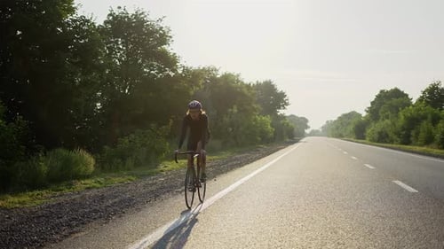 Un cycliste masculin en casque fait du vélo le long d'une piste vide