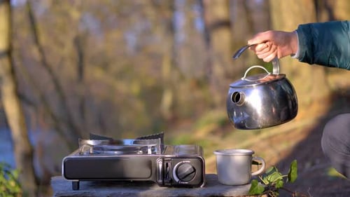 Person Pouring Water in Nature on Sunny Day