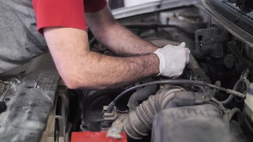 Mecánico trabajando, reparando el motor del automóvil con el capó abierto, procedimiento de cambio de aceite