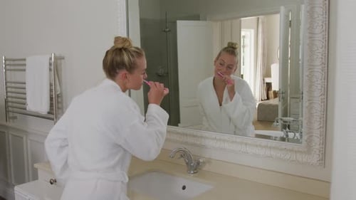 Woman Brushing Teeth in a Bright Bathroom