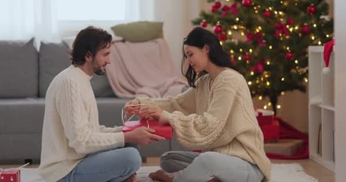 Young Couple Exchanging Christmas Gifts at Home