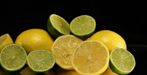 Fresh Lemons and Limes on Reflective Surface