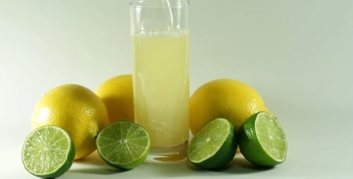 Lemon and Lime Juice Being Poured Into Glass