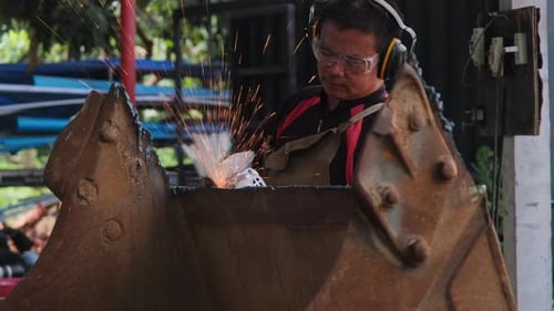 Professional men wearing welding mask and gloves work in home workshop with arc welding and argon.