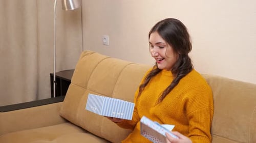 Woman Smiles Opening Gift at Home