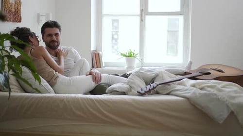 Couple Relaxing and Chatting on Bed Indoors