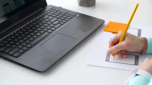 Person Designing Mobile App with Pencil on Paper