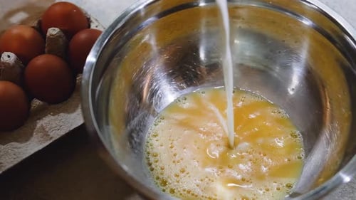 Milk Poured into Bowl of Eggs for Cooking