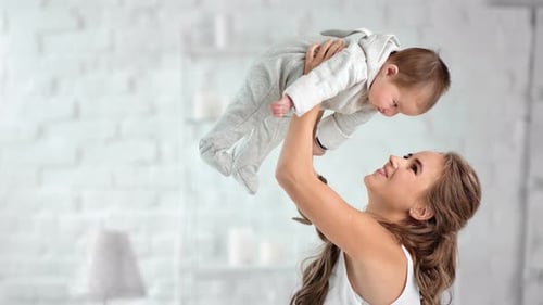 Happy Mother Lifting Baby in Bright Home