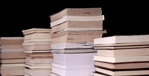 Stacks of Books Accumulating Against Black Backdrop