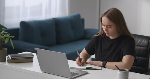 Woman Studying with Laptop and Notebook at Desk