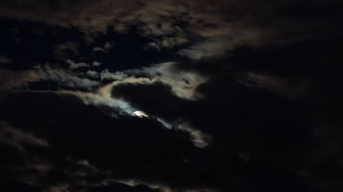 Full Moon Shines Through Dark, Cloudy Night Sky