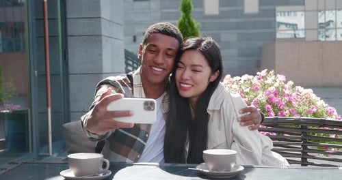 Smiling couple taking selfie at outdoor cafe