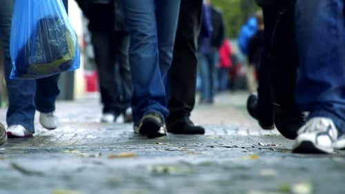 Zeitlupendetail der Beine von Personen, die auf dem Bürgersteig gehen
