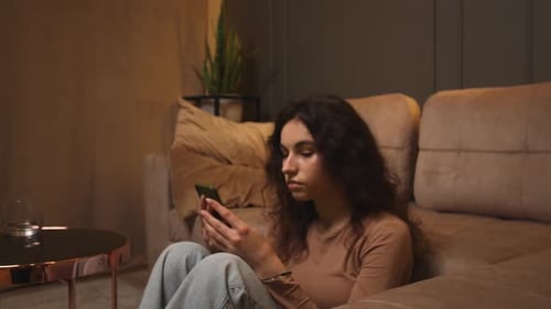 Pretty Smiling Caucasian Businesswoman Showing Smartphone with Green Screen Chromakey on Couch at