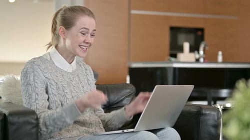 Woman Celebrates Success on Laptop at Home