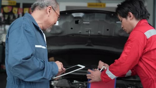Two male mechanic checking and repair the engine at car garage service, automobile technician