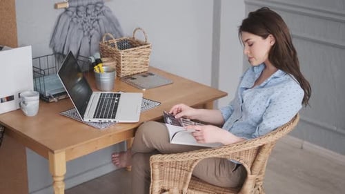 Woman Reading Book and Holding Photograph Indoors
