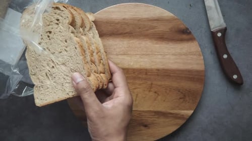 Hands Arranging Bread Slices on Wooden Board