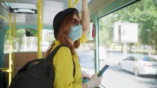 Woman Rides Bus Wearing Mask and Holding Phone