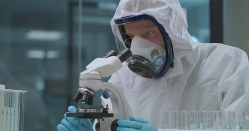 Scientist in Hazmat Suit Using Microscope in Lab