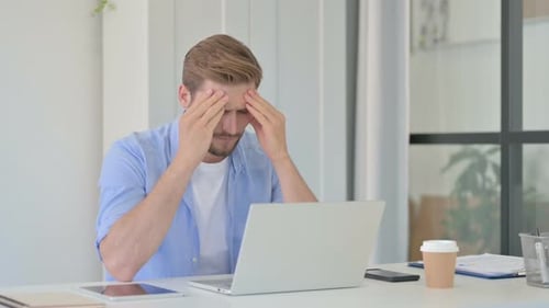 Man Typing at Desk Experiences Headache