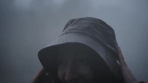 Person Laughing in Rain Wearing a Hat