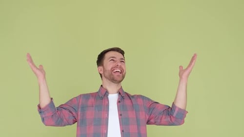 Man Smiling with Hands Raised Against Green Background