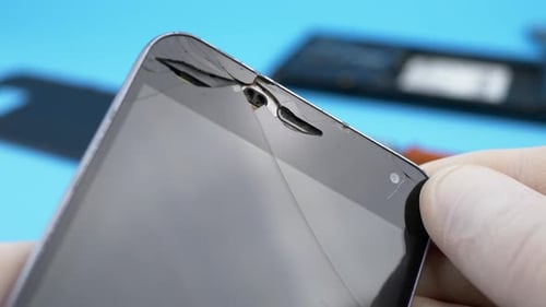 Cracked Cell Phone Screen Being Held Up Close