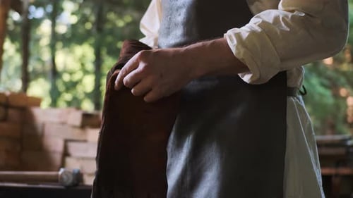 Worker Puts on Protective Glove in Outdoor Workshop