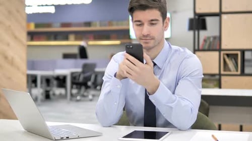 Young Adult Using Smartphone at Desk