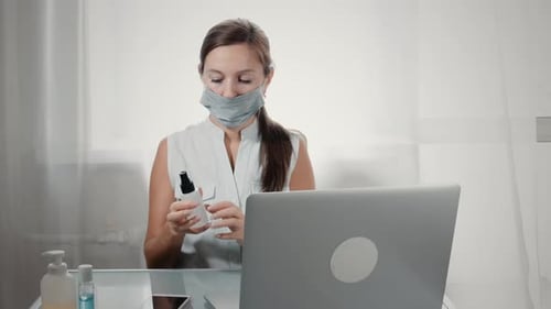 Young Adult Sanitizing Hands While Wearing Mask