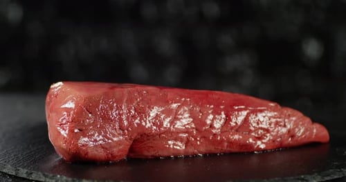 Raw Liver Rotating on Black Slate Surface
