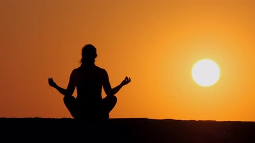 Woman Meditating on Beach at Sunset