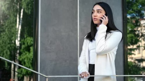 Confident Businesswoman Standing on Balcony Communicating Using Telephone