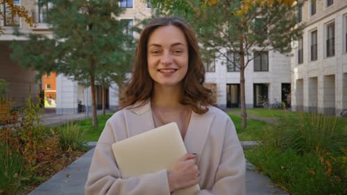 Smiling Woman Holding Laptop Computer Outside in City