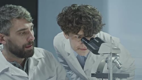 Scientists Collaborating with Microscope in Laboratory Setting