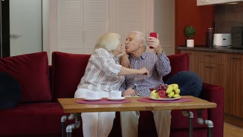 Smiling Senior Couple Using Smartphone on Couch