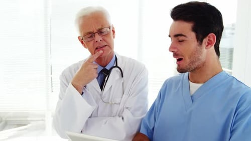 Male doctor and coworker discussing over digital tablet