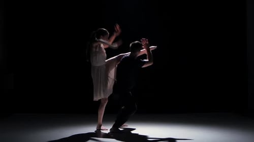 Acrobatic Dance Duo Performing in Dark Studio