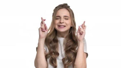 Young Woman Crosses Fingers Against White Background