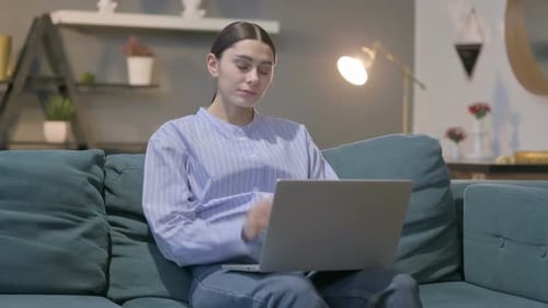 Woman on Couch Uses Laptop, Stretches Neck